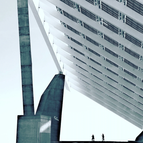Two people stand beneath a large, angled solar panel structure.