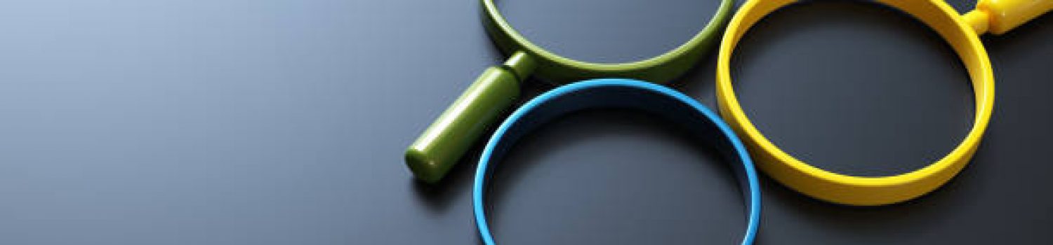 Three colorful magnifying glasses on a dark surface.