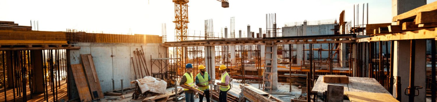 Experienced engineer explaining the problems in construction works – development after recession Construction site with crane and workers